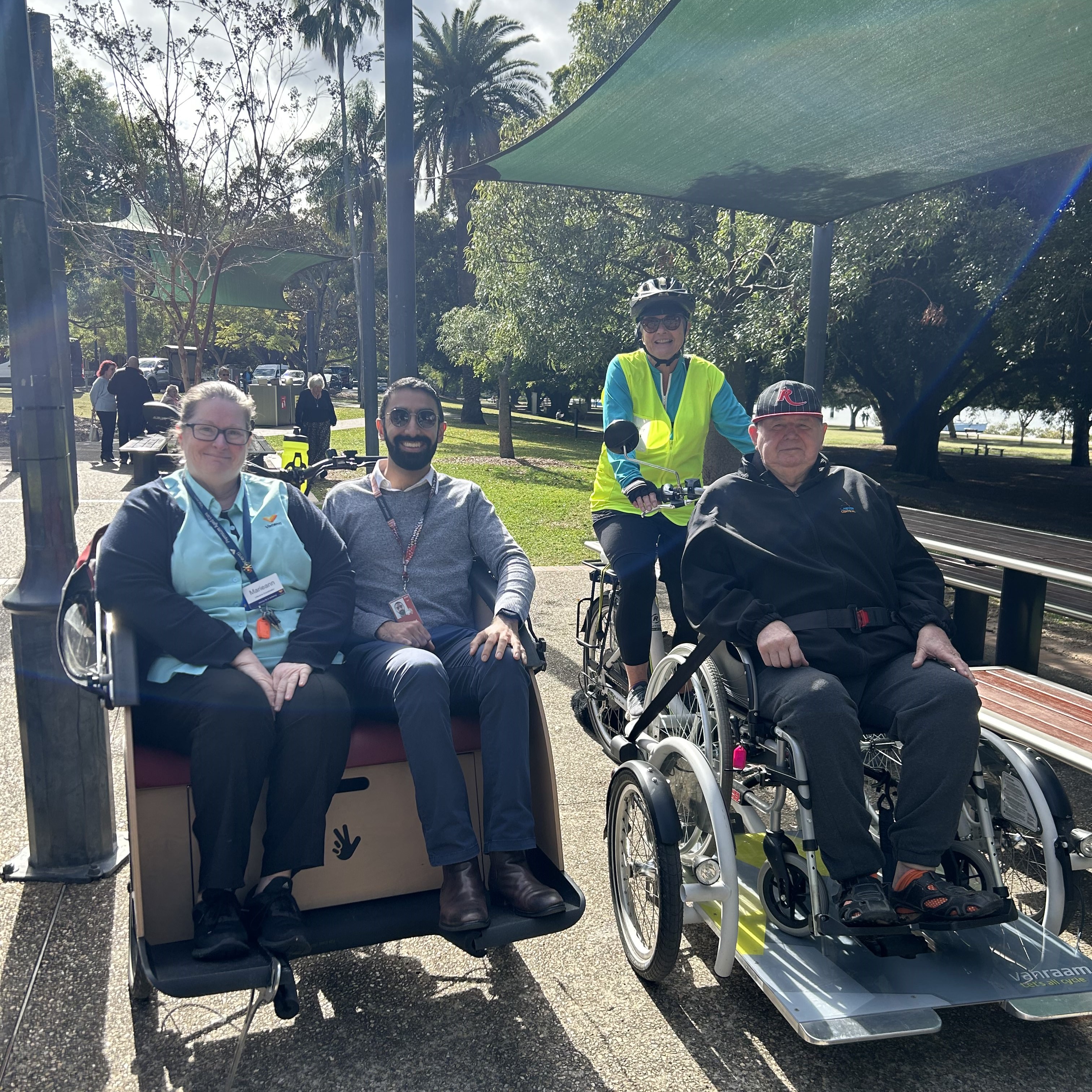 three people sitting in the front of the cycling without age bicycles, with one volunteer ready to peddle three people sitting in the front of the cycling without age bicycles, with one volunteer ready to peddle