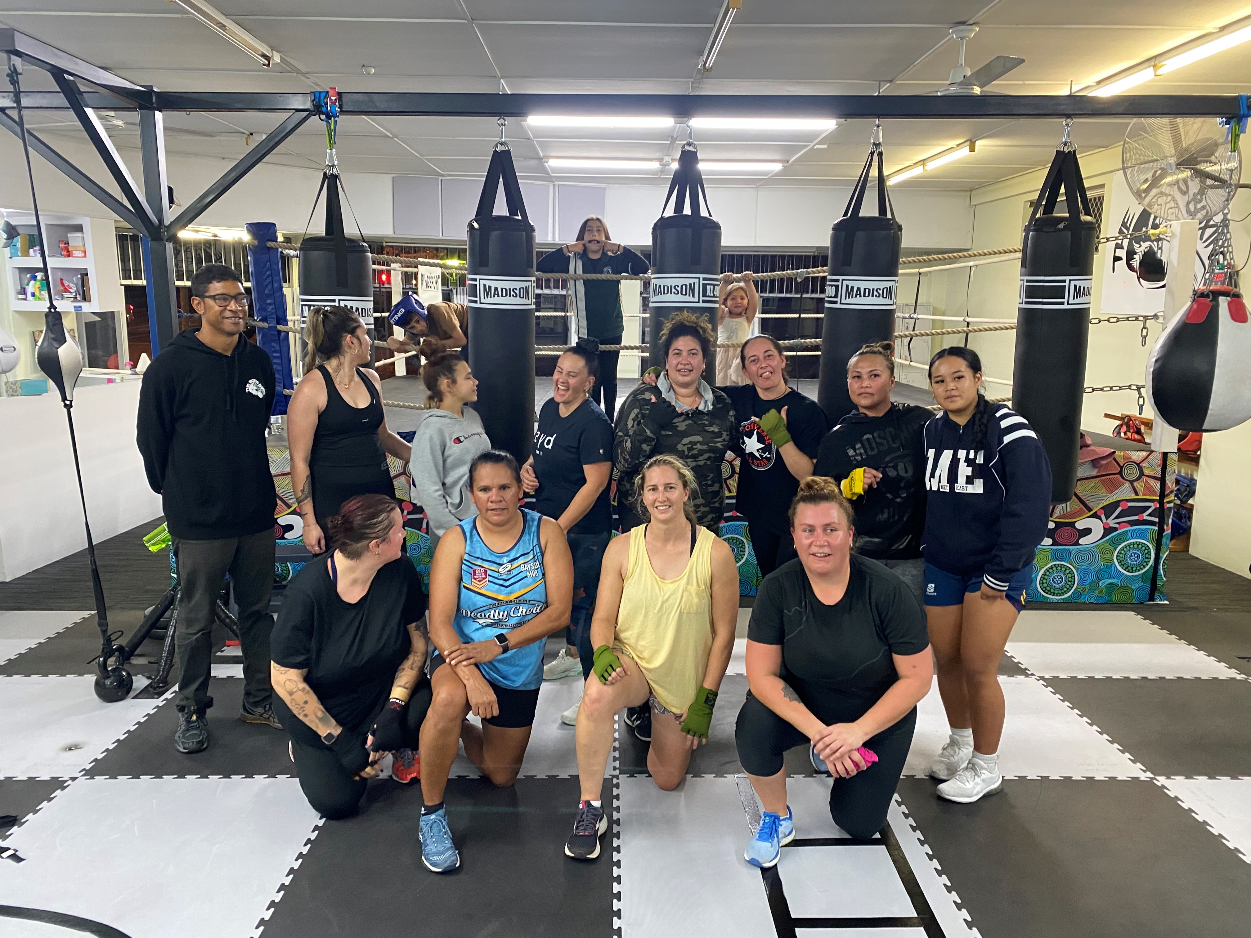 Group of boxers posing in front of punching bags Group of boxers posing in front of punching bags