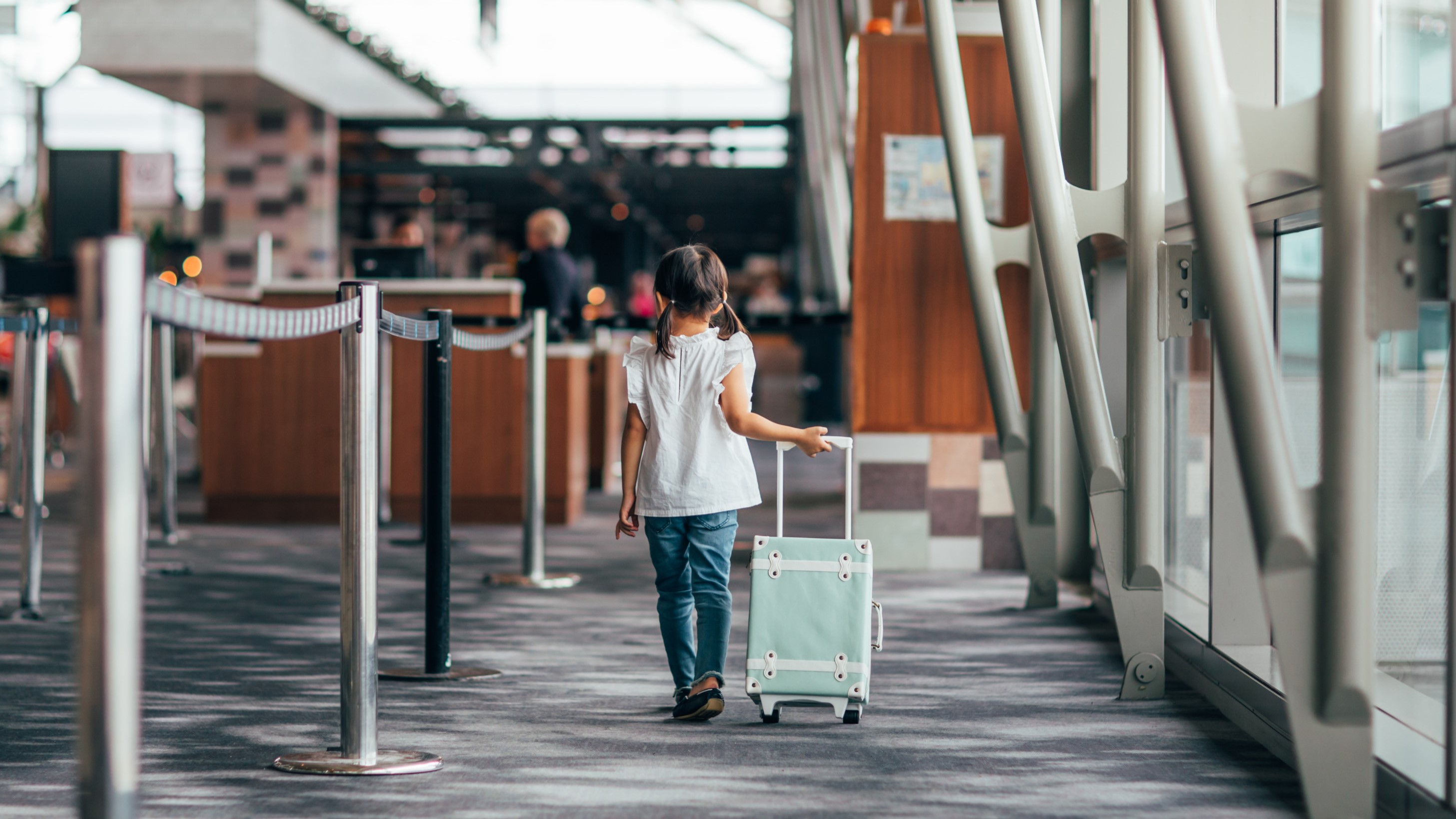 Child pulling a blue suitcase at the International Terminal Child pulling a blue suitcase at the International Terminal