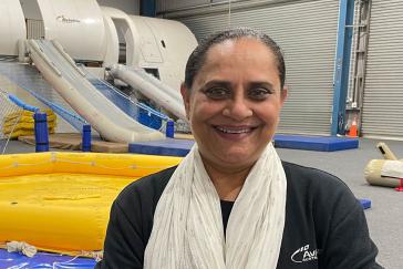 Harsha Patel standing in front of aviation training equipment - rafts and evacuation slides.  