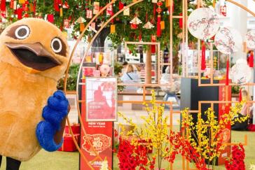 A person dressed in a kookaburra costume next to lunar new year decorations